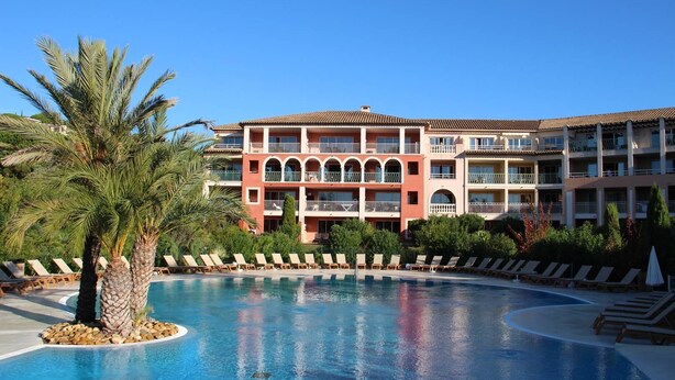 Un hôtel doté d’une piscine, de plusieurs balcons et d’un palmier.