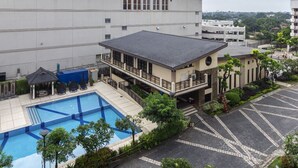 Ein Hotel mit Swimmingpool, überdachter Außenbestuhlung und Parkplatz.