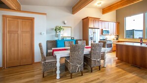 A modern kitchen with wooden cabinets, a central island, and a dining area with wicker chairs. - Blackberry Bramble 3 Bedroom Home by RedAwning (Hood River)