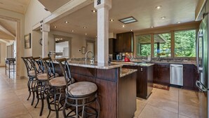 A spacious kitchen with a large island, bar stools, and a view of the outdoors. - Luxury Mountain Chalet with Elevator & Hot Tub, Dog Friendly (Durango)