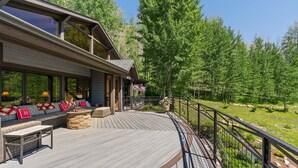 A modern house with a wooden deck, outdoor seating, and a view of a forested area. - Luxury Mountain Chalet with Elevator & Hot Tub, Dog Friendly (Durango)