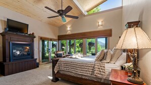 A spacious bedroom with a large bed, a fireplace, and a view of the outdoors. - Luxury Mountain Chalet with Elevator & Hot Tub, Dog Friendly (Durango)