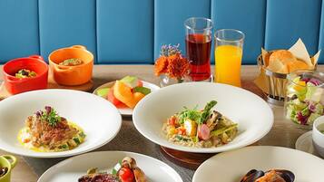 Una mesa servida con diversos platos, incluyendo mariscos y verduras, y dos vasos de jugo.