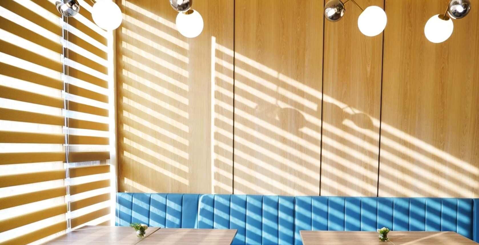 A modern interior with wooden panel walls, blue cushioned seating, and pendant lighting.