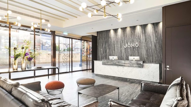Un área de recepción moderna con una pared de mármol, un mostrador de recepción y arreglos de asientos.