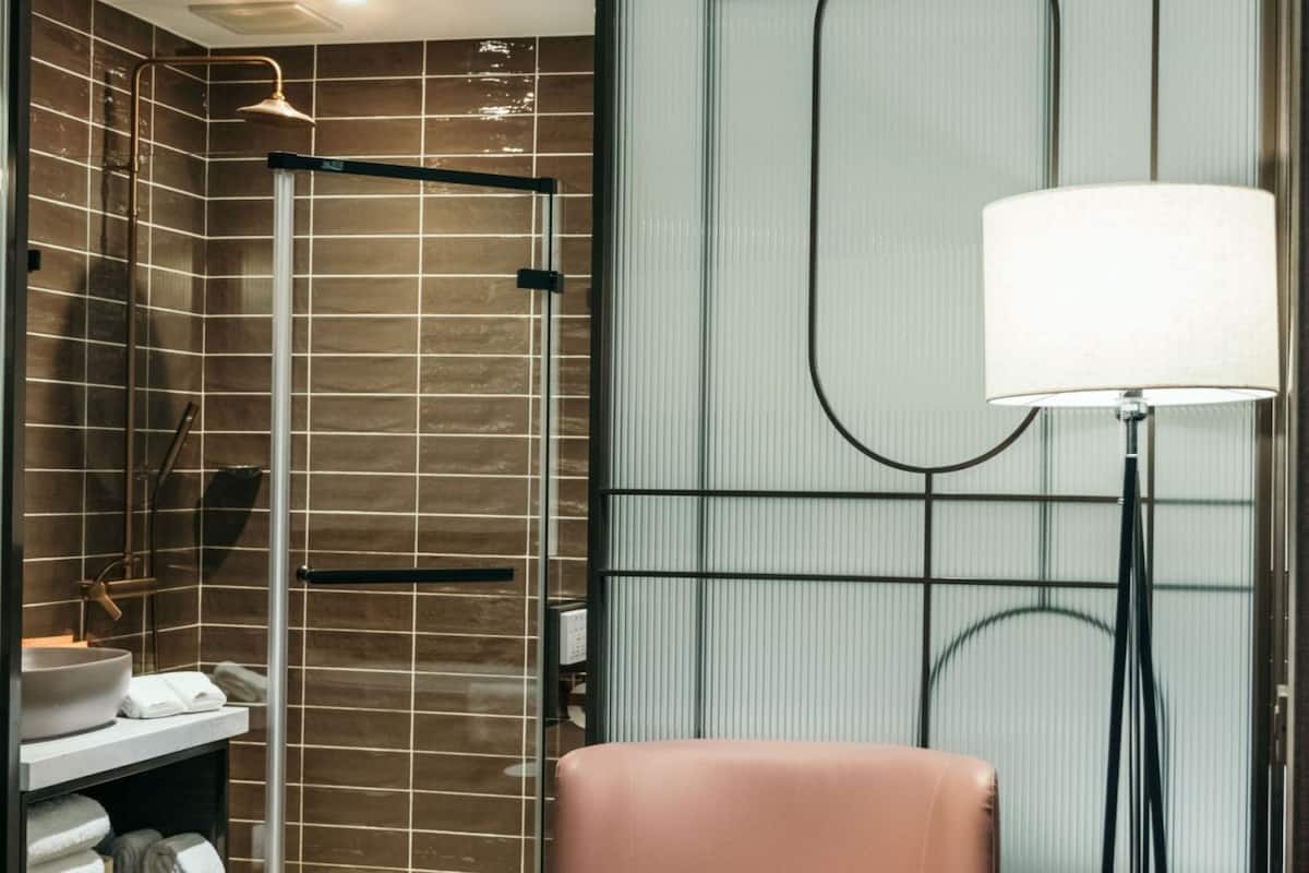 Un baño moderno con un espejo grande, un lavamanos y una zona de ducha.