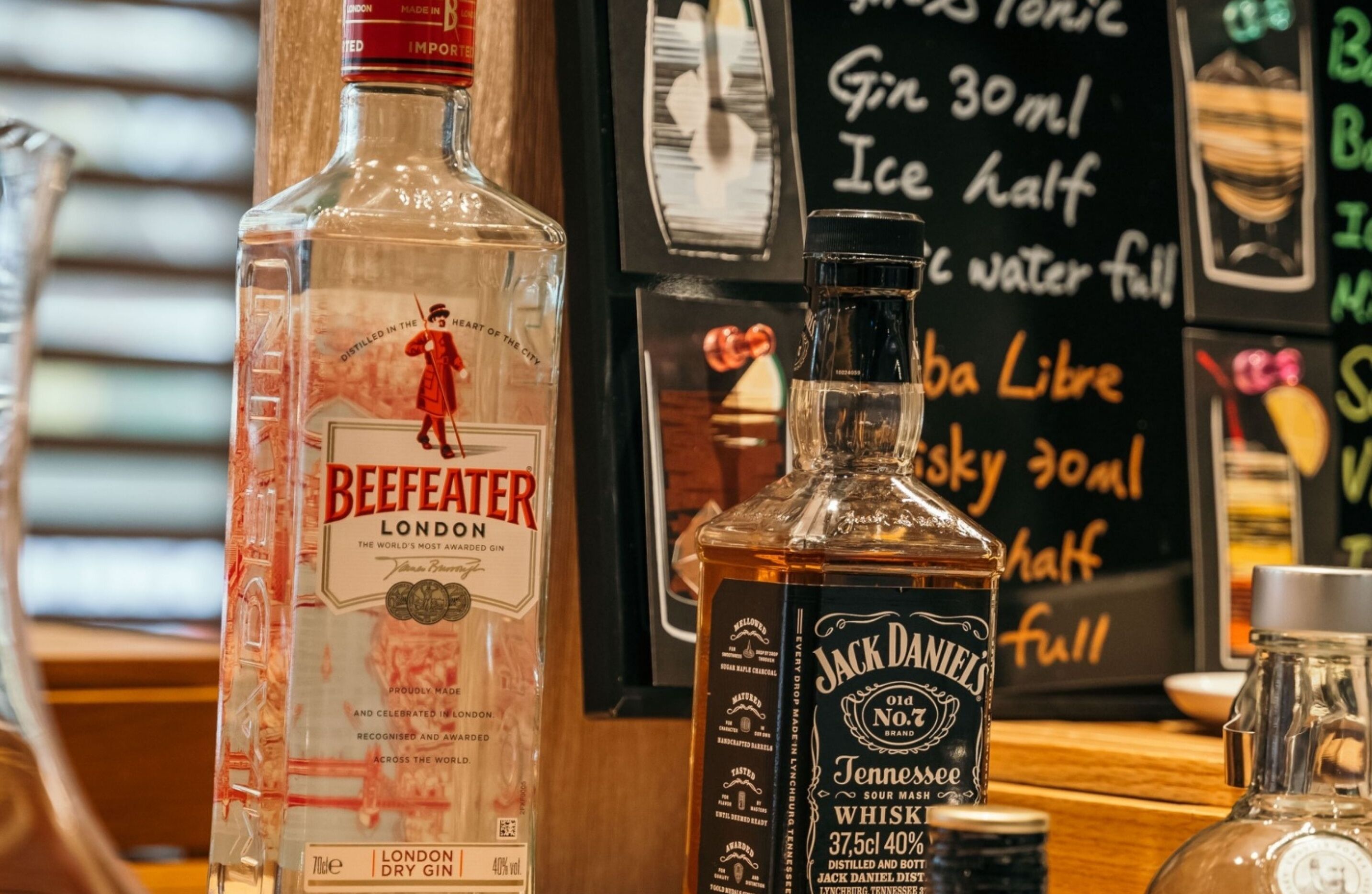 Bottles of London Dry Gin and Jack Daniel's Tennessee Sour Mash Whiskey on a bar counter.