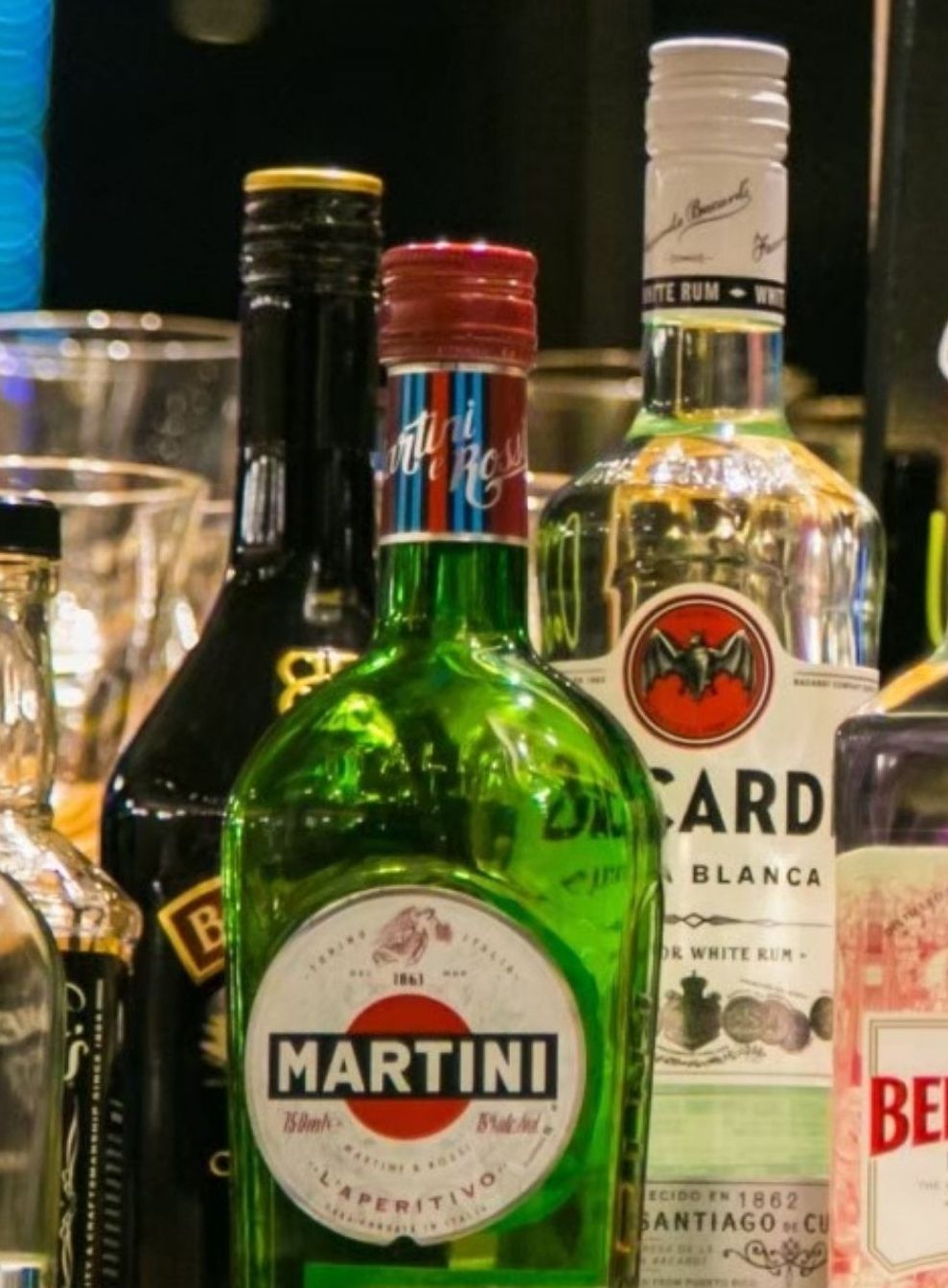 A variety of liquor bottles, including Martini, on a shelf.
