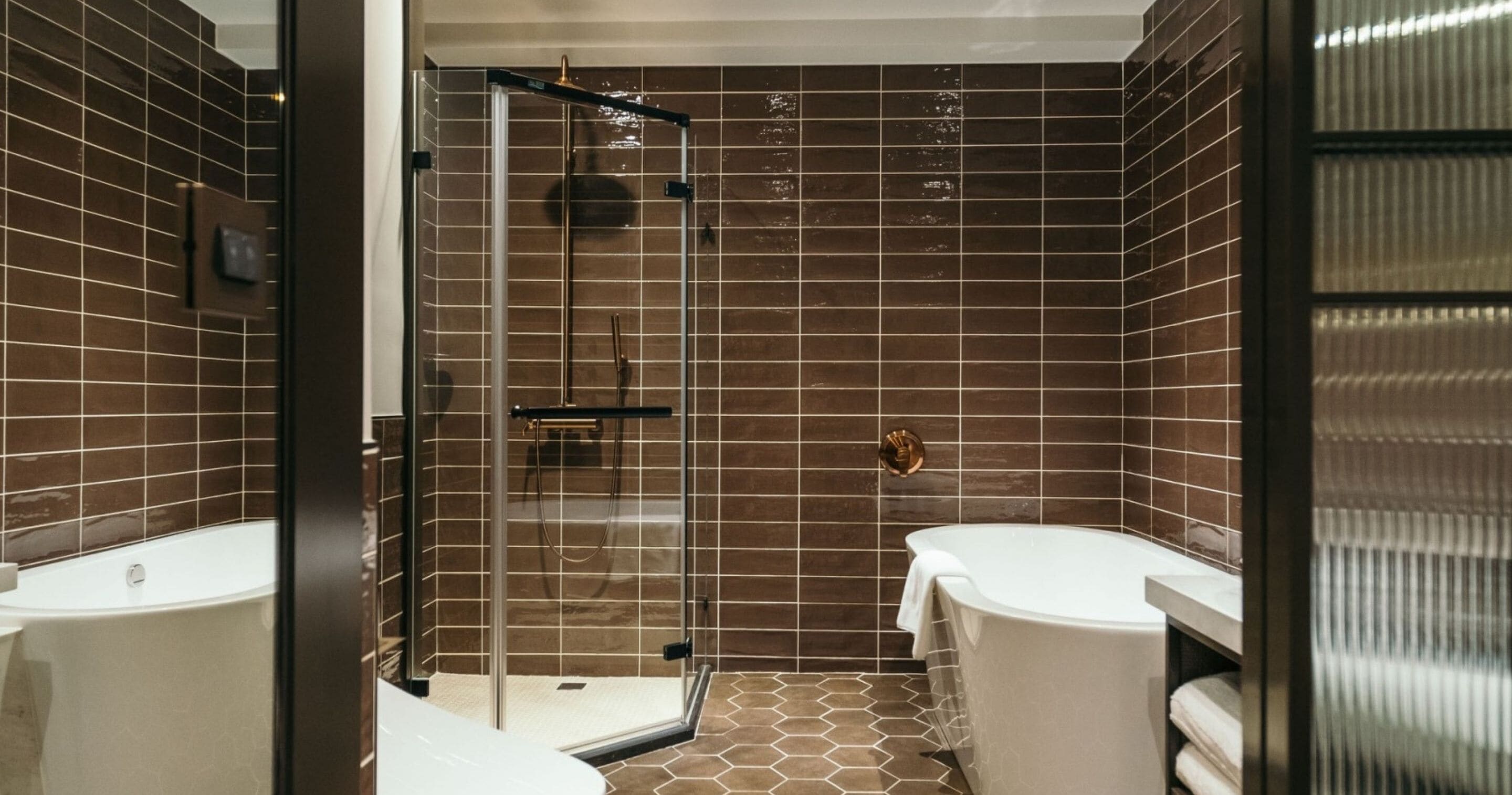 A modern bathroom with a glass-enclosed shower, a white bathtub, and a toilet.