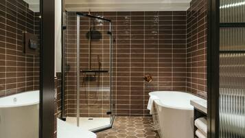 A modern bathroom with a glass-enclosed shower, a white bathtub, and a toilet.