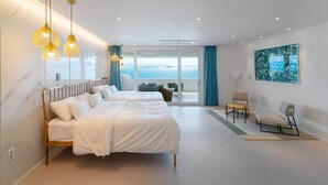 Une chambre d’hôtel moderne avec un grand lit, un balcon offrant une belle vue et un tableau accroché au mur.