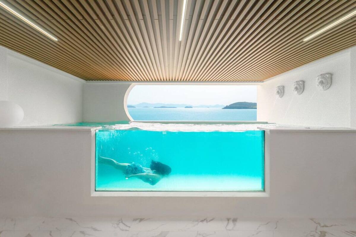 A modern room with a large window, a view of the sea, and a wooden ceiling.
