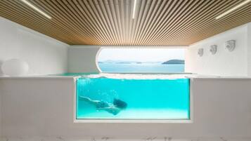 Una habitación moderna con un ventanal grande, vista al mar y techo de madera.