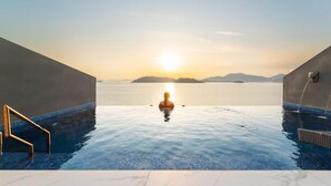 Une personne dans une piscine à débordement, avec une vue sur le coucher de soleil.