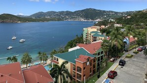 A coastal hotel with a view of the sea, a swimming pool, and a parking area.