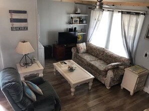A living room with a sofa, a coffee table, a TV, and a small cabinet.