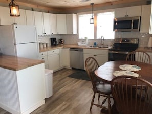 Kitchen features a dishwasher, stove, microwave, sink, and dining table with four chairs.