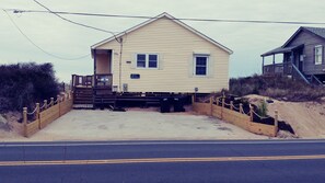 Situated on a sandy beach, this beach house features a front porch and a small deck area, perfect for taking in the views.