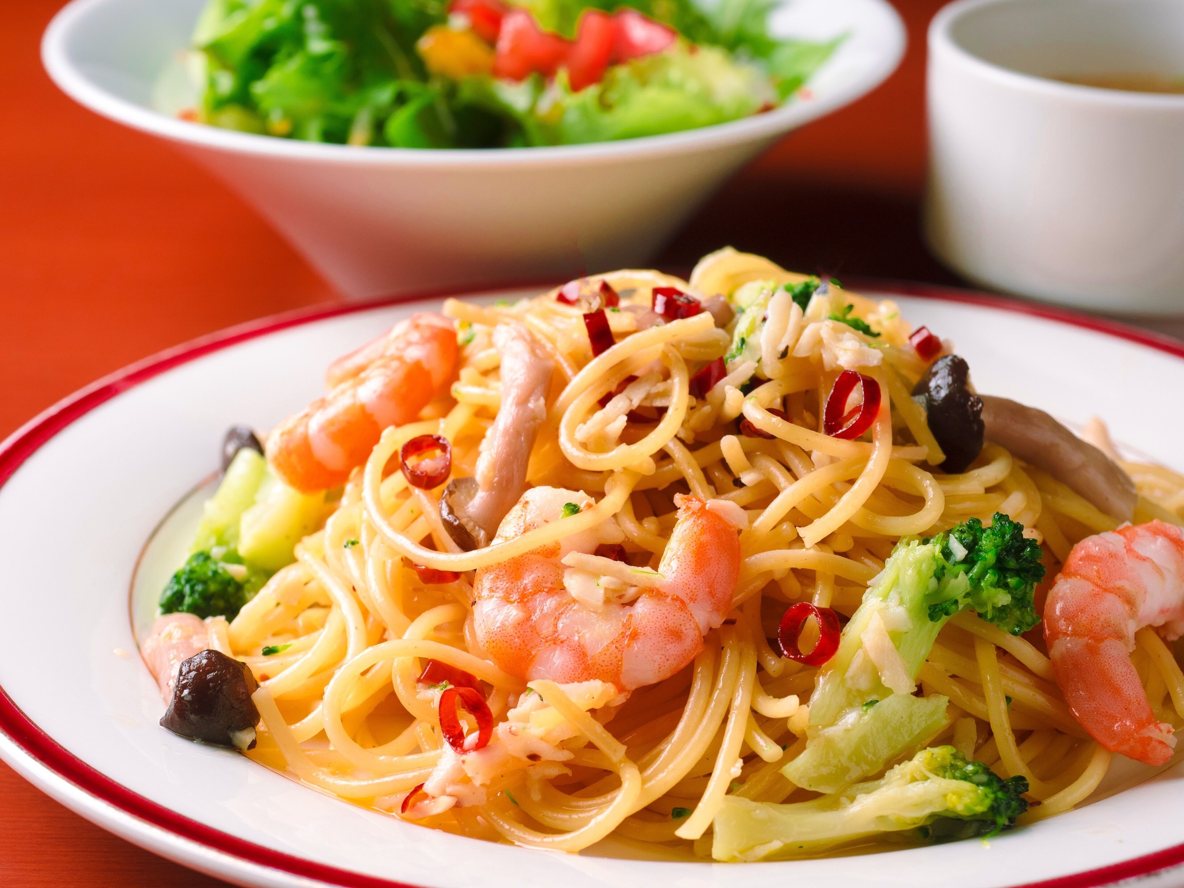 Une assiette de spaghettis aux crevettes, aux brocolis et aux piments rouges.