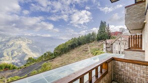 Un balcon doté d’un plancher en verre donnant sur un paysage montagneux.