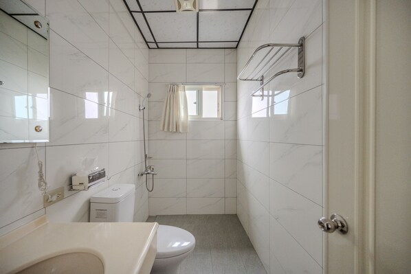 Un baño con inodoro, lavamanos y zona de ducha.