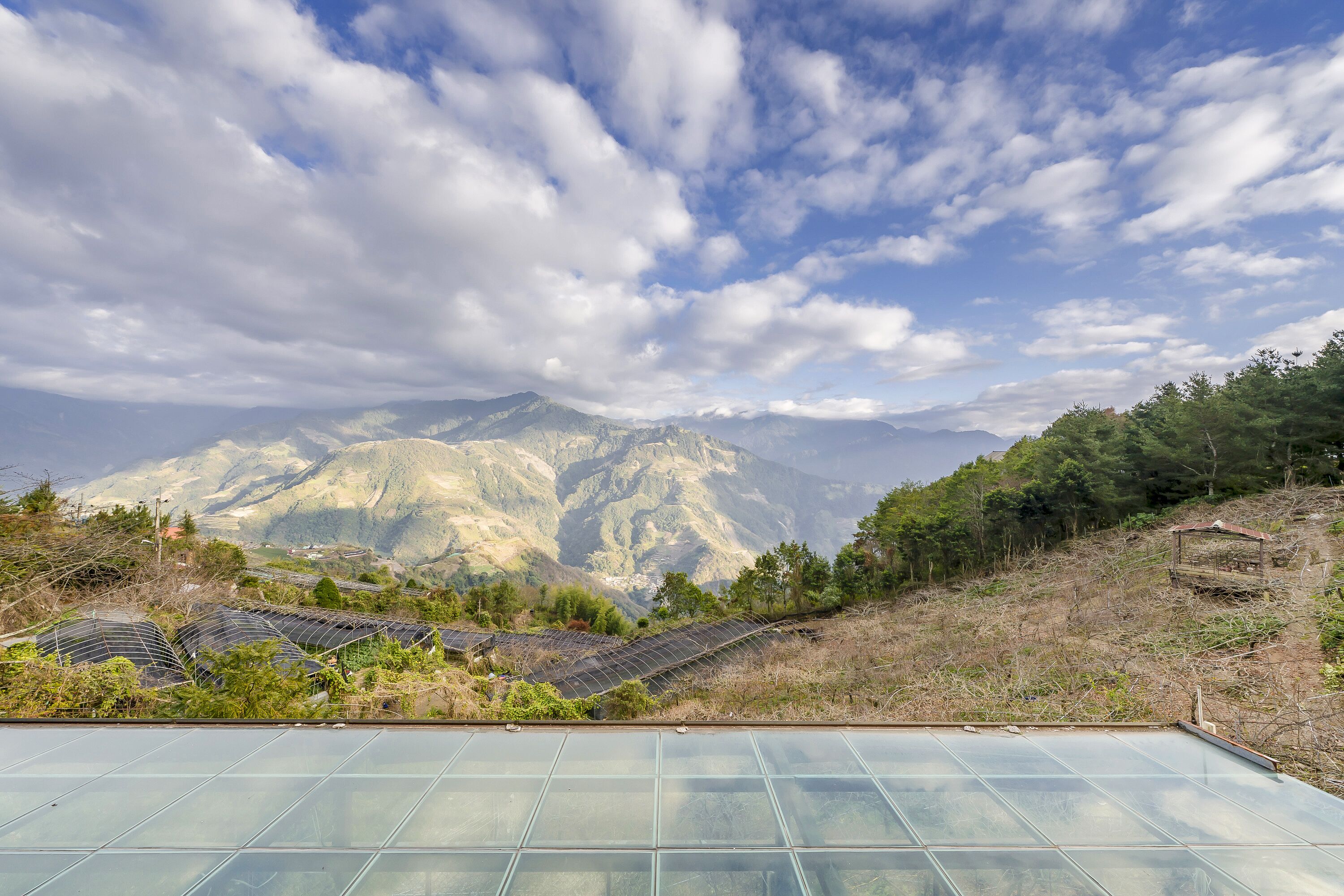 A greenhouse with solar panels and a view of mountains.