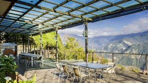An outdoor patio with a table and chairs, a grill, and a view of mountains. - Chingjing New Paradise B&B (Ren'ai)