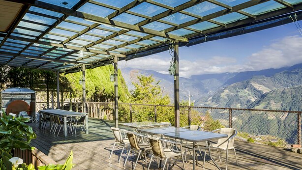 Une terrasse extérieure avec une table et des chaises, un barbecue et une vue sur les montagnes.