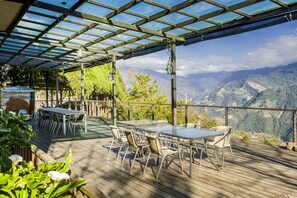 Un patio exterior con mesa y sillas, una parrilla y vistas a las montañas.