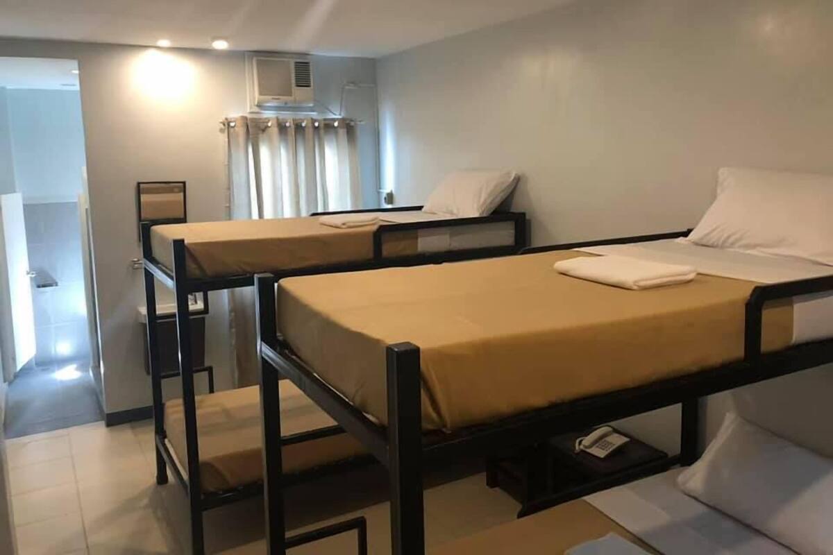A room with two bunk beds, a small table with a phone, and a window with curtains.
