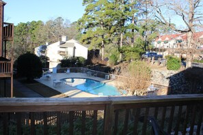 Relax by the pool surrounded by mature trees and a stone wall, perfect for a peaceful retreat.