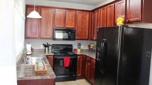 A kitchen with wooden cabinets, a black refrigerator, a stove, a microwave, and a sink. - Beautiful Lake View Condo. Minutes to Racetrack (Hot Springs)