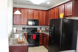 Kitchen features a stove, microwave, and refrigerator, along with a sink and dish rack.