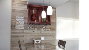A kitchen with a granite countertop, wooden wall paneling, a wine rack with glasses, and a small decorative box. - Beautiful Lake View Condo. Minutes to Racetrack (Hot Springs)