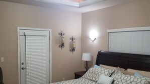 A bedroom with a bed, a ceiling fan, a nightstand, a lamp, and a door with blinds. - Beautiful Lake View Condo. Minutes to Racetrack (Hot Springs)