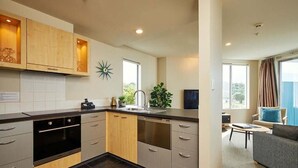 Eine moderne Küche mit grauen Schränken, einem Geschirrspüler und einer Spüle. Es gibt einen Essbereich mit einer grauen Couch und einem kleinen Tisch.