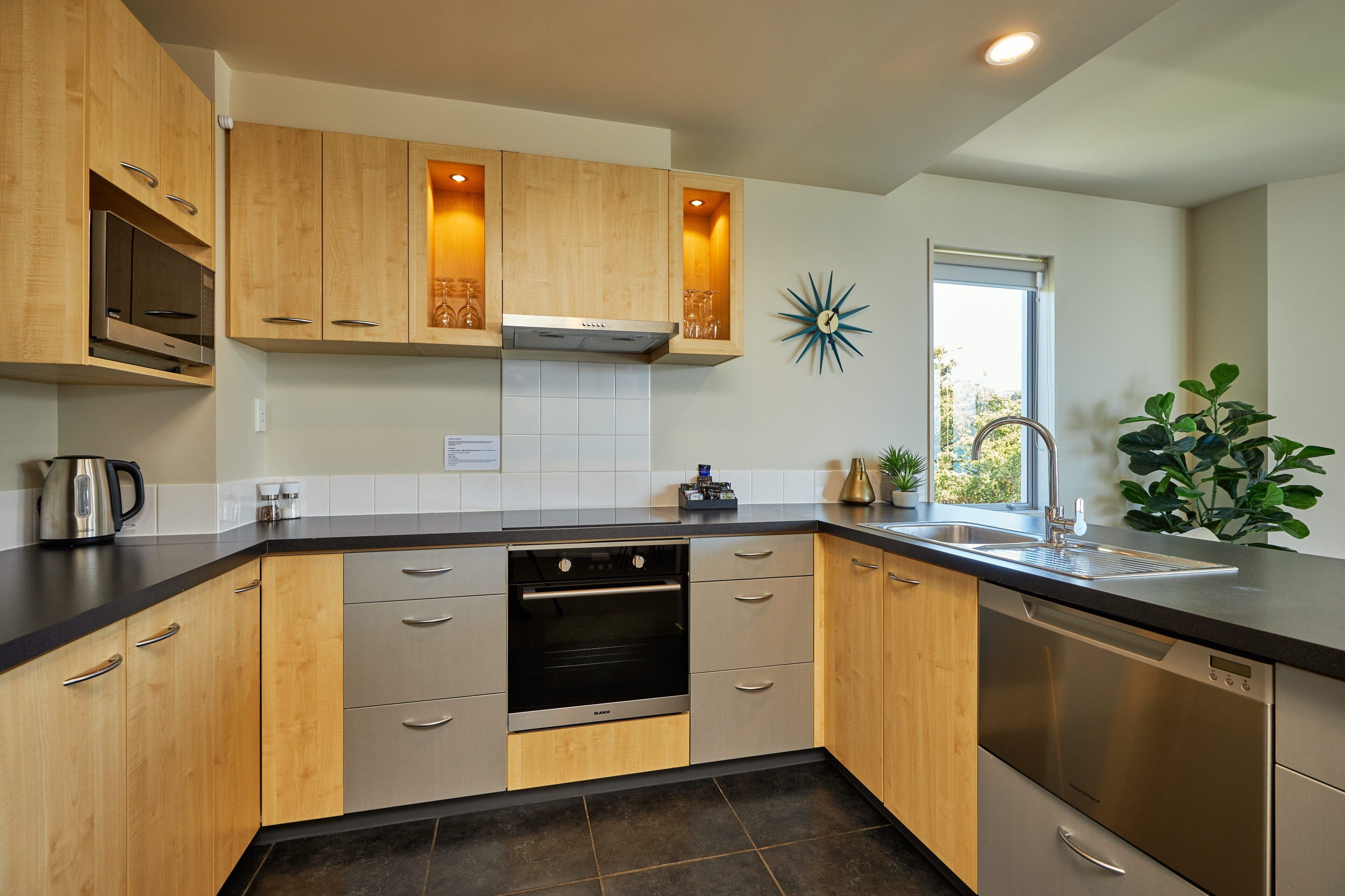 A modern kitchen with wooden cabinets, stainless steel appliances, and a window providing natural light.