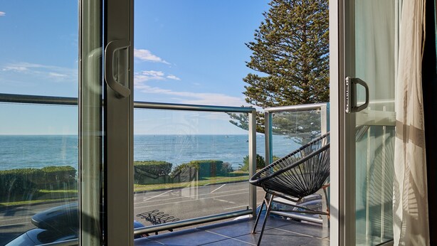 Ein Balkon mit Meerblick, einem Stuhl und einer Glastür.