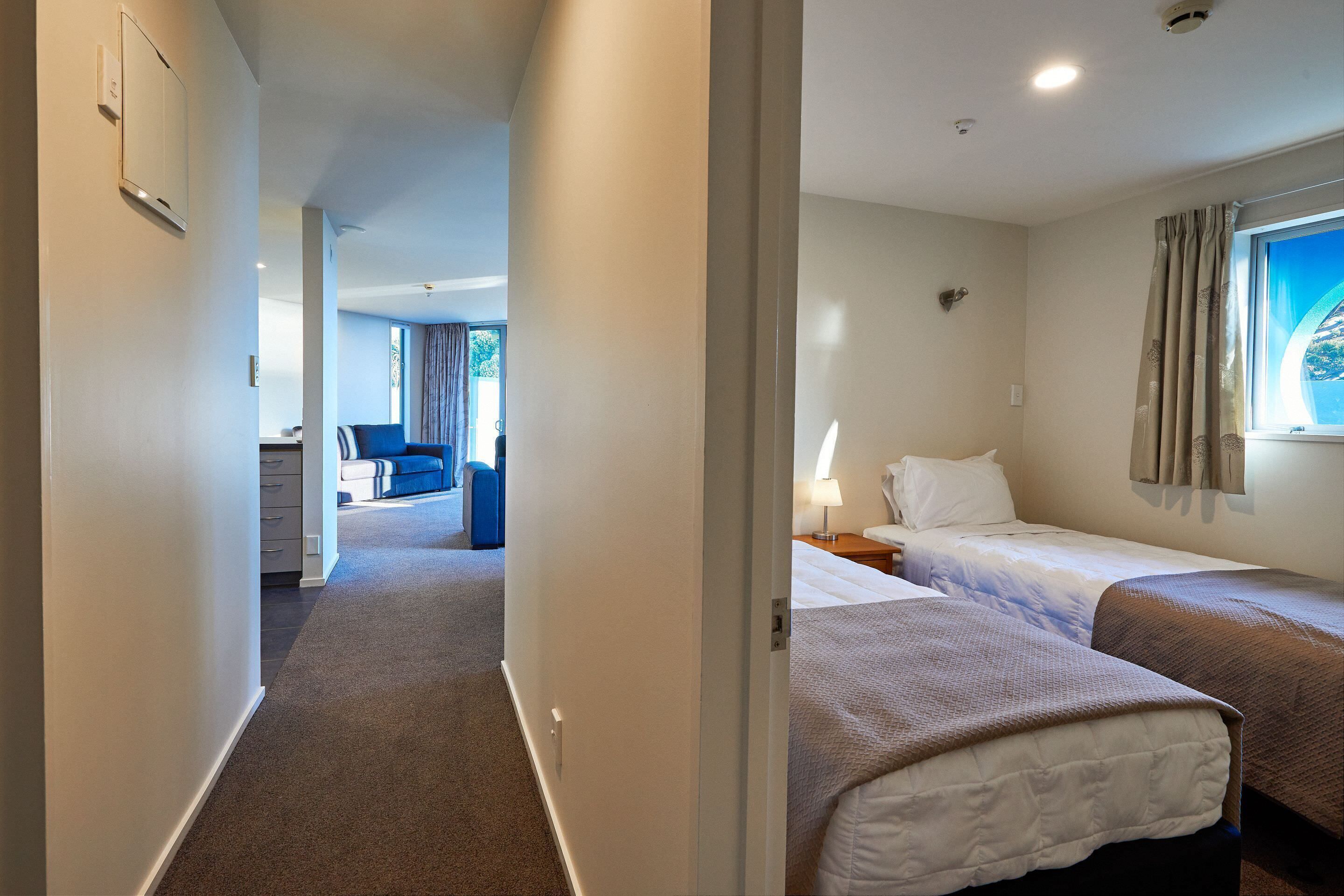 Een hotelkamer met twee bedden, een bureau en uitzicht op de omgeving.