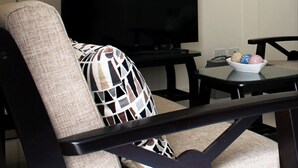 A living room with a sofa, a TV, a coffee table, and decorative items on shelves. - Townhome with 24Hr Security in Panglao Island (Dauis)