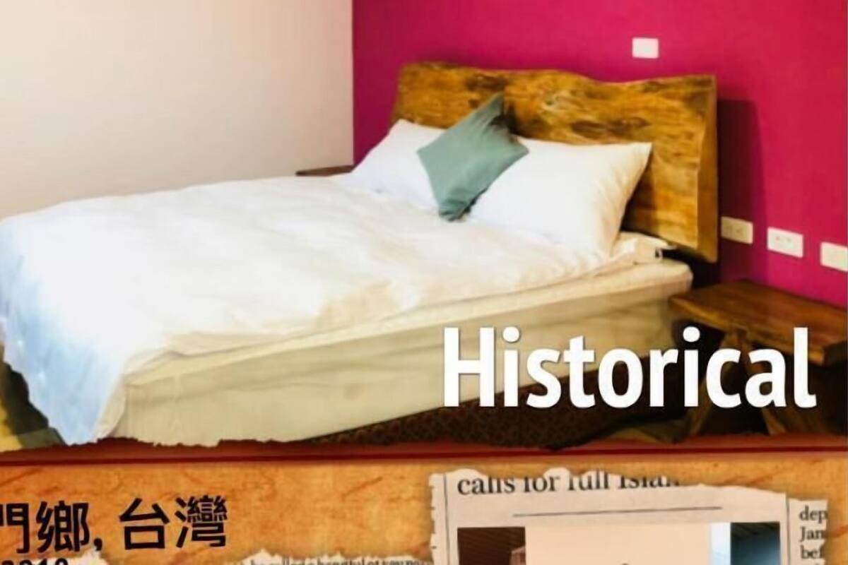 A bed with a wooden headboard, white bedding, and a blue pillow.