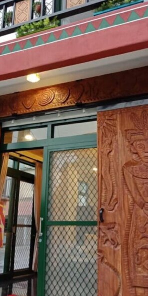 A building entrance with a green door, a mesh window, and a decorative wooden panel. - Dja Lji An Homestay (Sandimen)