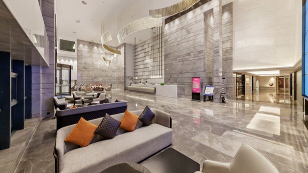 A spacious lobby with a reception desk, seating area, and a large wall with a grid pattern. - Tianyuan Junlong Hotel (Xiamen)