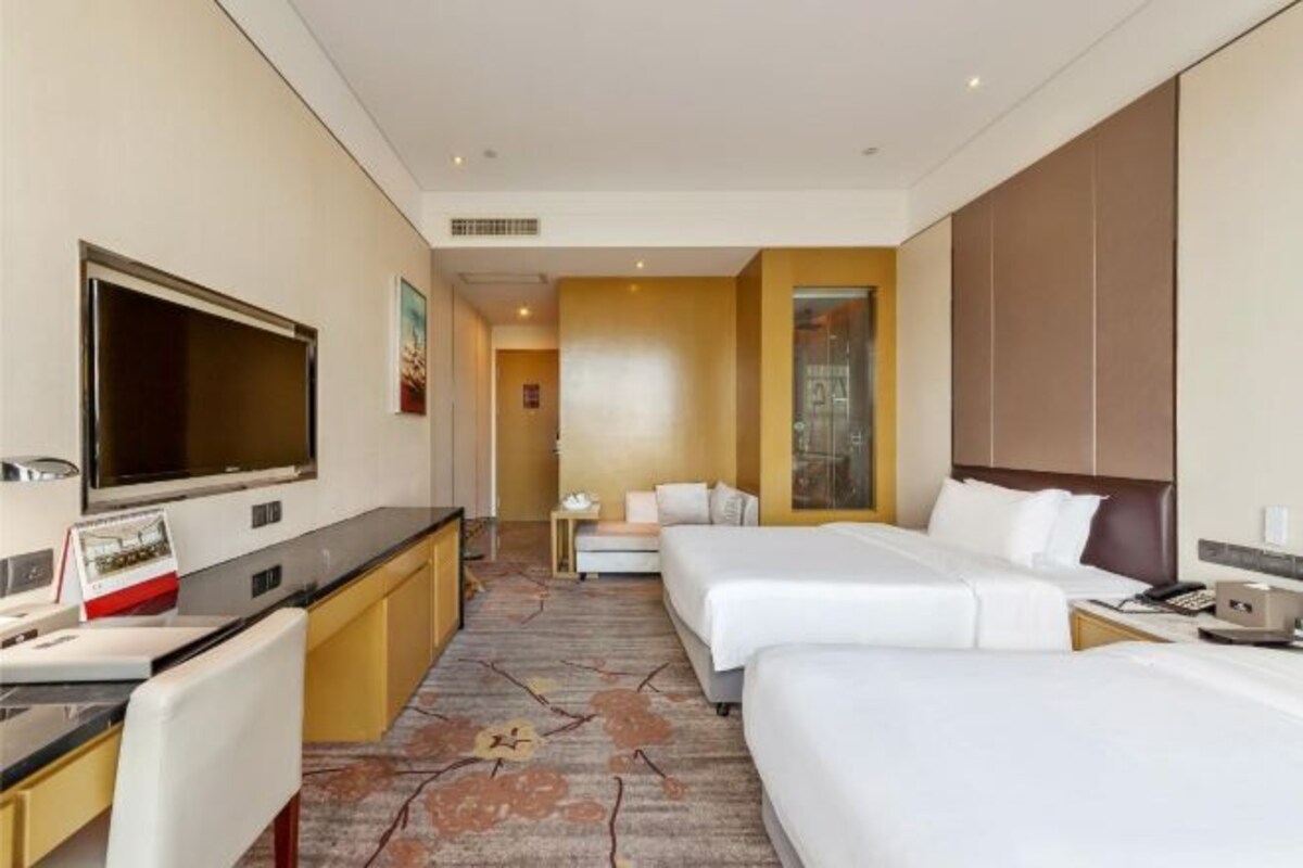 A hotel room with a bed, a desk, a TV, and a bathroom.