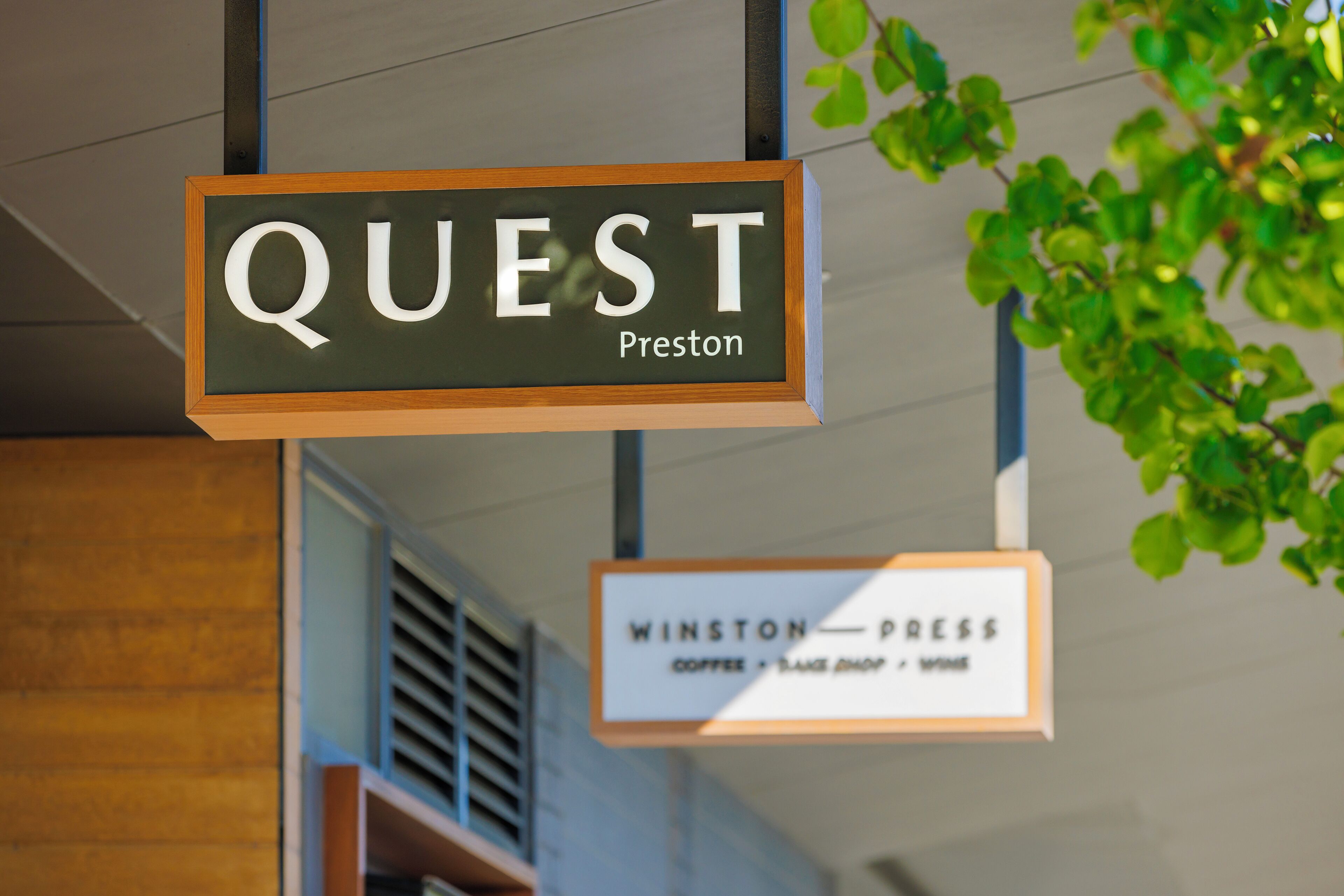 A sign for 'QUEST Preston' and 'WINSTON PRESS' with a coffee shop, bookstore, and wine bar.