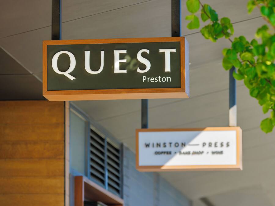 A sign for 'QUEST Preston' and 'WINSTON PRESS' with a coffee shop, bookstore, and wine bar.