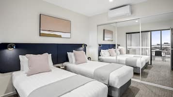 Habitación de hotel con dos camas, un espejo grande y vistas a la ciudad.