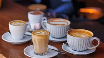 Una mesa con varias tazas de café, cada una con un diseño y decoración de arte latte diferentes.