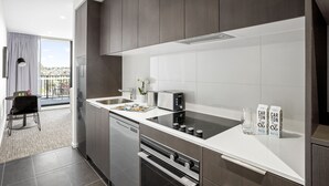 A modern kitchen with dark wood cabinets, a white countertop, a built-in oven, and a dishwasher.