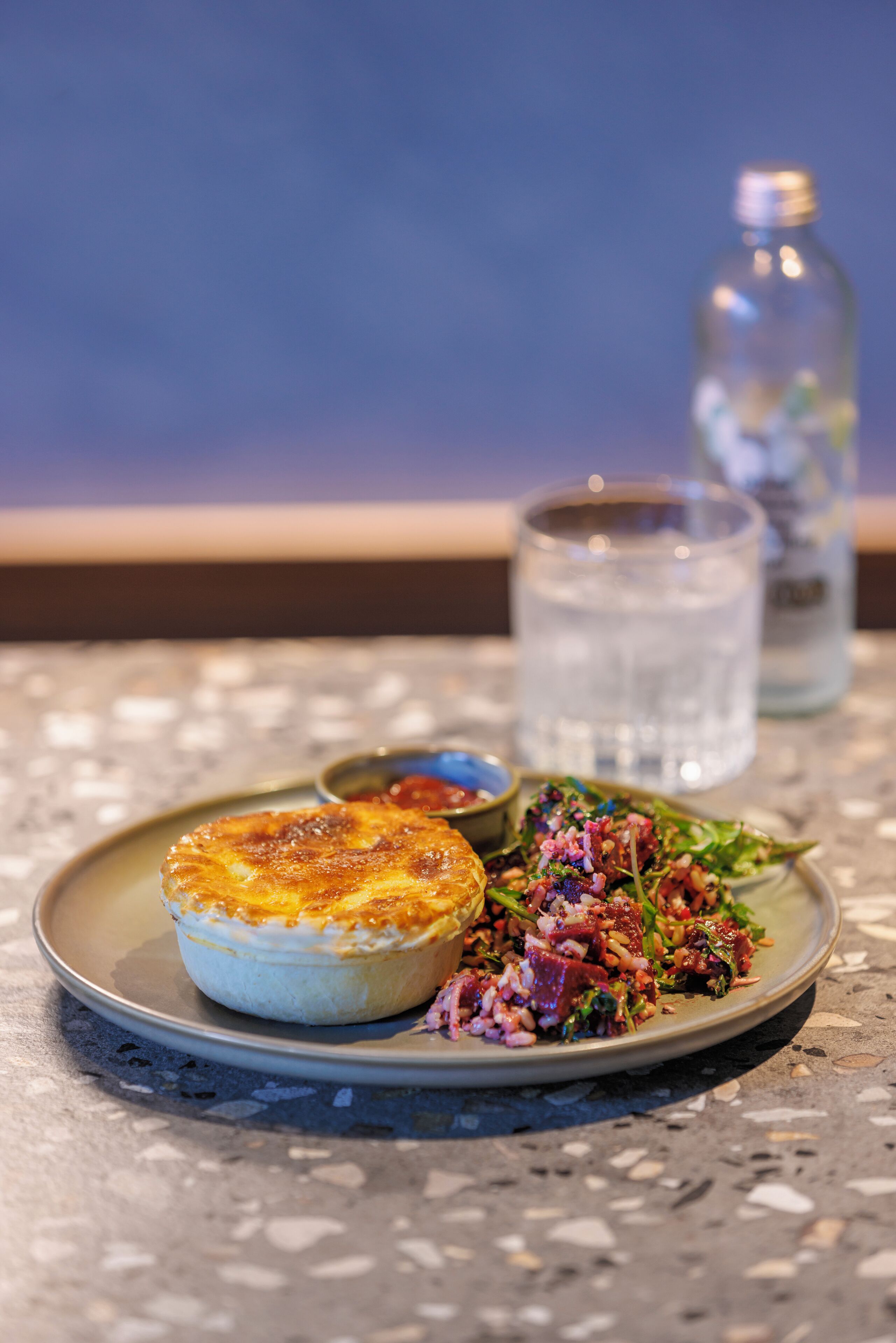 Um prato com um pastel e salada sobre uma mesa estampada.